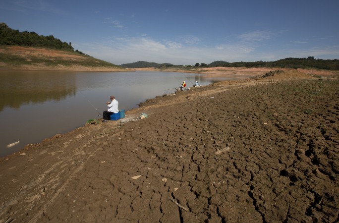 Fisherman sit on cracked land at Sao Paulo dam