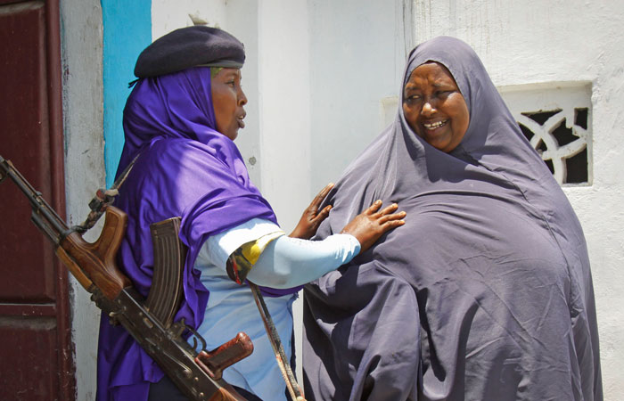 A female Somali soldier, left, searches a civilian before she enters a police station in Mogadishu, the nation's capital, on Sunday, March 30, 2014. There are at least 1,500 women serving in the Somali army, though most are not allowed to fight on the front lines.