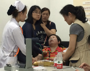 A relative of Shanghai passengers on board a cruise ship that capsized in central China, is attended to by a medical worker as she waits for answers at a government office in Shanghai, China, Tuesday, June 2, 2015. Relatives storm a government office to demand for action after the tourist agency which organized the tour failed to help them. (AP Photo)