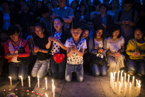 Locals and relatives of passengers onboard the capsized cruise ship pray during a candle light vigil in Jianli county, in southern China's Hubei province, Thursday. Rescuers cut three holes into the overturned hull of a river cruise ship in unsuccessful attempts to find more survivors Thursday.  (Chinatopix Via AP) 