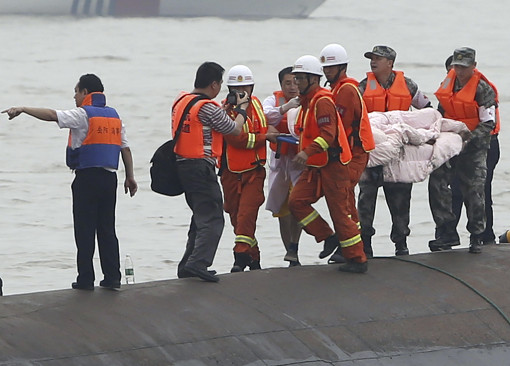 Rescuers carry a survivor pulled from the capsized cruise ship on the Yangtze River in Jianli in central China's Hubei province Tuesday June 2, 2015. Divers on Tuesday pulled survivors from inside the overturned cruise ship, state media said, giving some small hope to an apparently massive tragedy with well over 400 people still missing on the river. (Chinatopix Via AP)