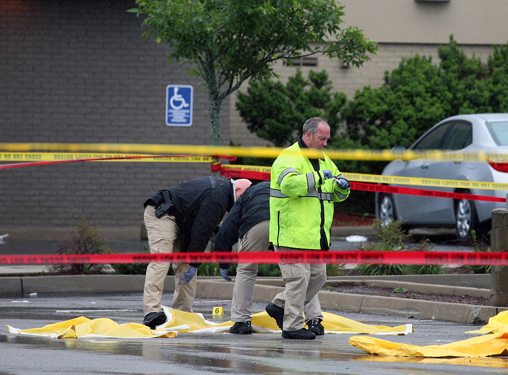 Boston police officers and detectives investigate at the scene of a shooting Tuesday morning, June 2, 2015) at 4600 Washington St. in Roslindale, Mass. A man under surveillance by terrorism investigators has been shot and killed by a Boston police officer. Police Commissioner William Evans confirmed from the scene that the man shot at about 7 a.m. at a pharmacy in the city's Roslindale neighborhood has died. Evans said the man was under surveillance by the Joint Terrorism task Force.  (Mark Garfinkel/The Boston Herald via AP) 